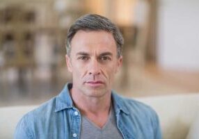 closeup of a middle aged man with a receding hairline contemplating treatment